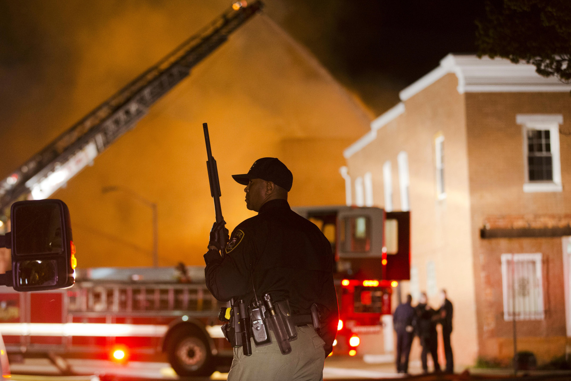An officer stands near a blaze, Monday, April 27, 2015, after rioters plunged part of Baltimore into chaos, torching a pharmacy, setting police cars ablaze and throwing bricks at officers. (AP Photo/Matt Rourke)