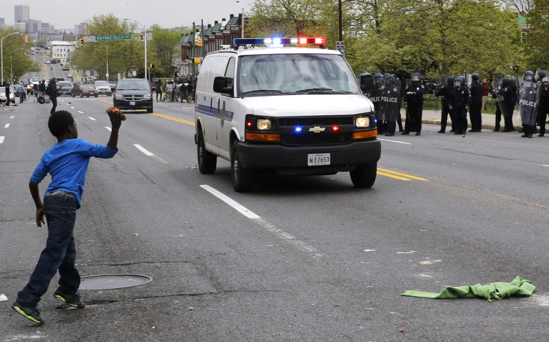 A boy throws a brick at a police van, Monday, April 27, 2015, during a skirmish between demonstrators and police after the funeral of Freddie Gray in Baltimore. Gray died from spinal injuries about a week after he was arrested and transported in a Baltimore Police Department van. (AP Photo/Patrick Semansky)