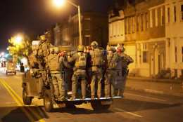 Police ride on an armored vehicle through the area where Monday's riots occurred following the funeral for Freddie Gray, after a 10 p.m. curfew went into effect, Tuesday, April 28, 2015, in Baltimore. (AP Photo/David Goldman)