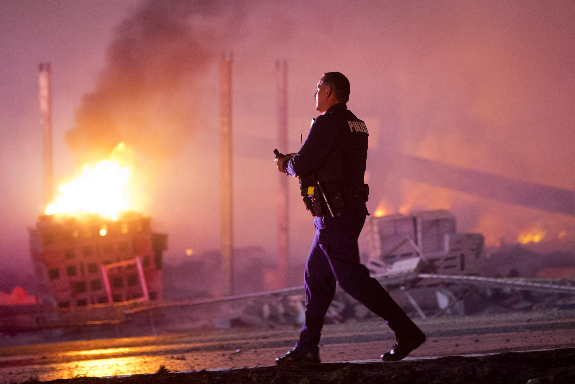 A police officer walks by a blaze, Monday, April 27, 2015, after rioters plunged part of Baltimore into chaos, torching a pharmacy, setting police cars ablaze and throwing bricks at officers. (AP Photo/Matt Rourke)