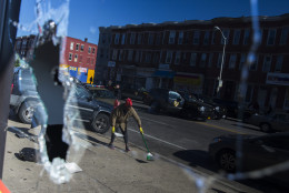 Residents clean up after an evening of riots on Tuesday, April 28, 2015, in Baltimore.  National Guard troops fanned out through the city, shield-bearing police officers blocked the streets and firefighters doused still-simmering blazes early Tuesday as a growing area of Baltimore shuddered from riots following the funeral of Freddie Gray who died in police custody. (AP Photo/Evan Vucci)