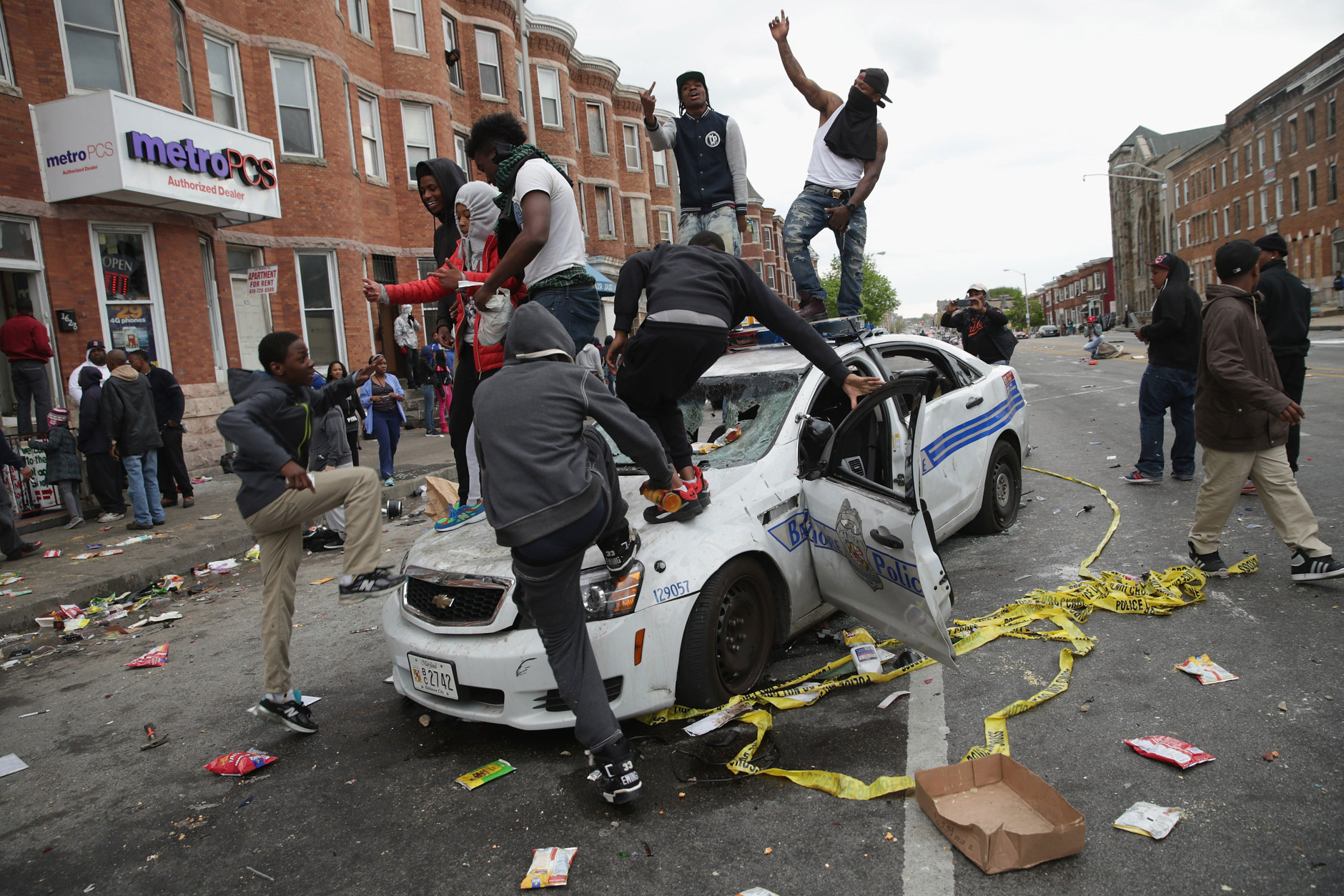 BALTIMORE, MD - APRIL 27: Demonstrators climb on a destroyed Baltimore Police car in the street near the corner of Pennsylvania and North avenues during violent protests following the funeral of Freddie Gray April 27, 2015 in Baltimore, Maryland. Gray, 25, who was arrested for possessing a switch blade knife April 12 outside the Gilmor Homes housing project on Baltimore's west side. According to his attorney, Gray died a week later in the hospital from a severe spinal cord injury he received while in police custody. (Photo by Chip Somodevilla/Getty Images)