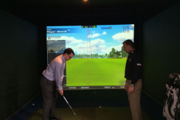 Golf professionals gave tips as players practiced shots on a simulator. (WTOP/Noah Frank)