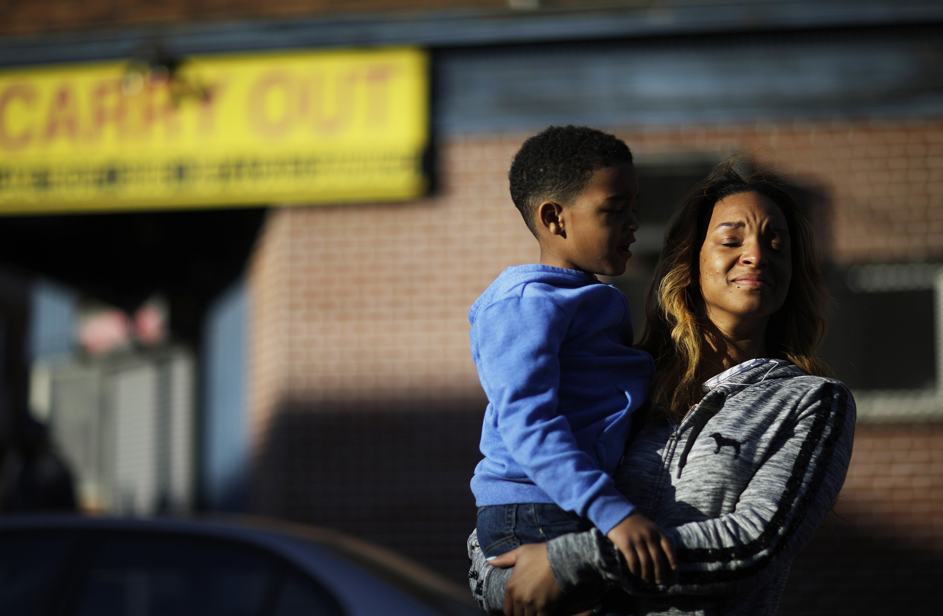 Cierra Powell fights back tears as she holds her son, Keon Lovitt, 6, as they pause to listen to an outdoor church service a block from Monday's riots that followed the funeral for Freddie Gray, who died in police custody, Tuesday, April 28, 2015, in Baltimore. (AP Photo/David Goldman)