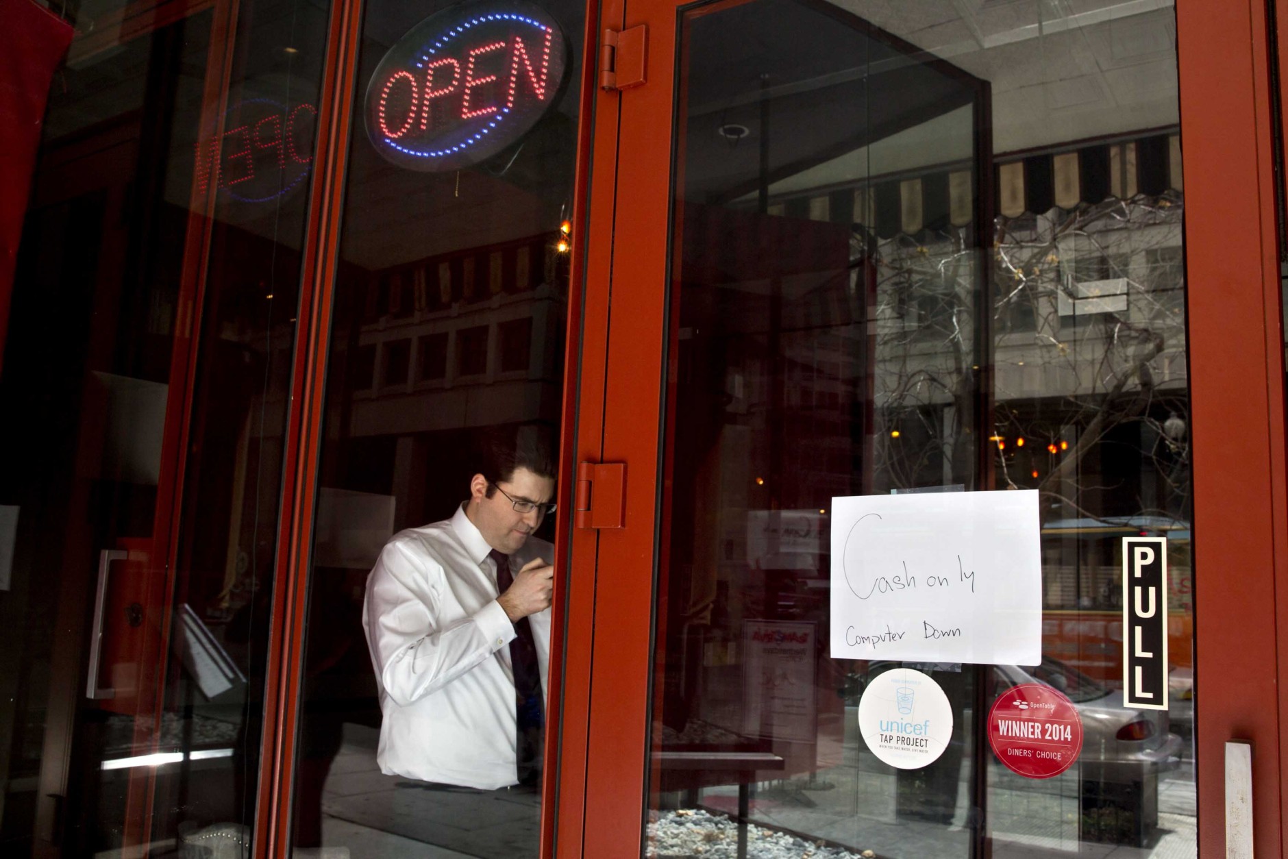 A man checks his cellphone in a restaurant with a sign advertising that the computer is down, as power returns after a brief power outage, Tuesday, April 7, 2015, in Washington. The White House, State Department, and Capitol were all affected by reports of widespread power outages across Washington and its suburbs Tuesday afternoon.  (AP Photo/Jacquelyn Martin)