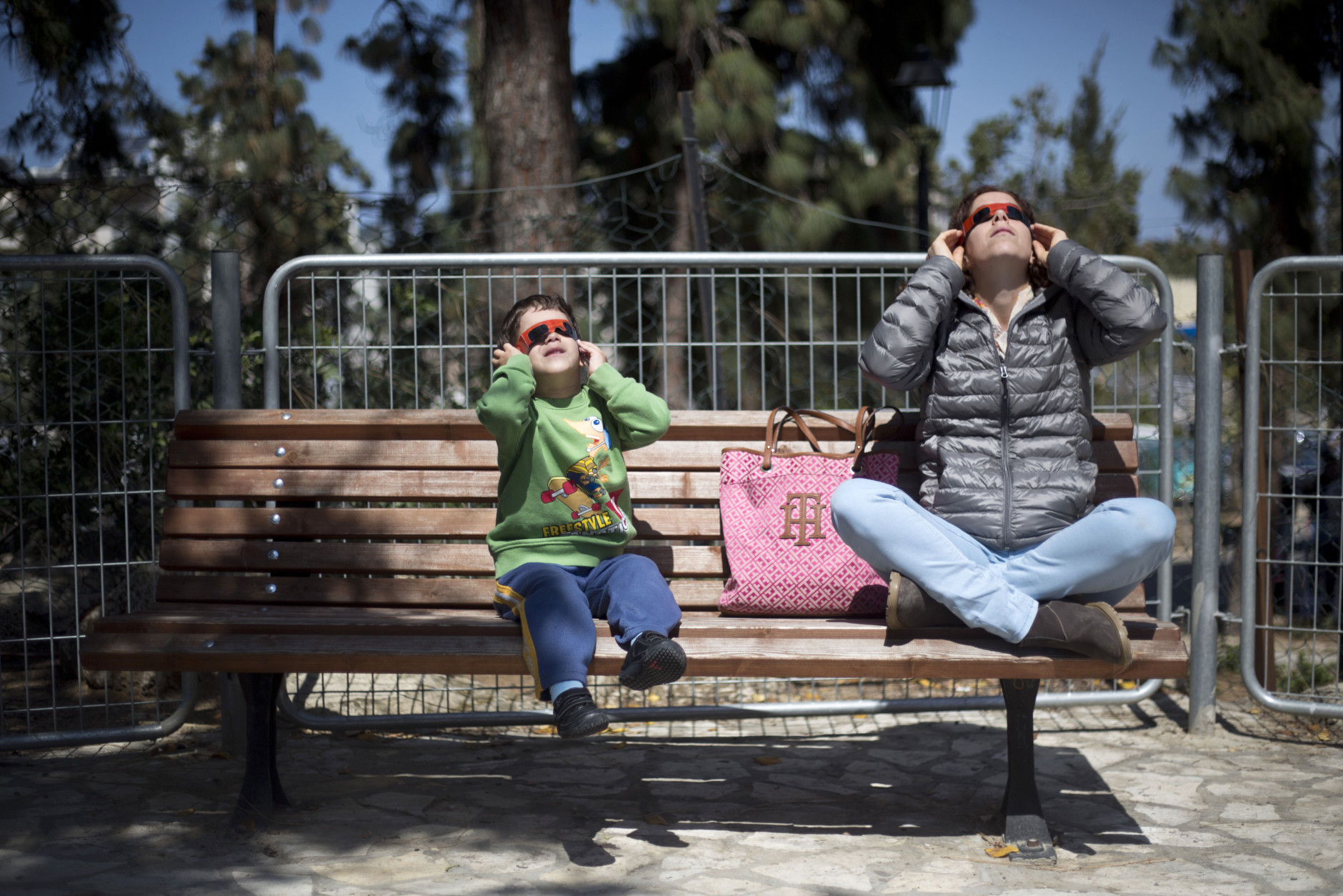 FILE - In this Friday, March 20, 2015 file photo, an Israeli mother and son look up at the sun wearing protective goggles to watch a partial solar eclipse in the town of Givatayim, near Tel Aviv, Israel. The partial eclipse was visible across Europe and parts of Asia and Africa, while sky-gazers in the Arctic were treated to a perfect view of a total solar eclipse as the moon completely blocked out the sun in a clear sky. (AP Photo/Ariel Schalit, File)