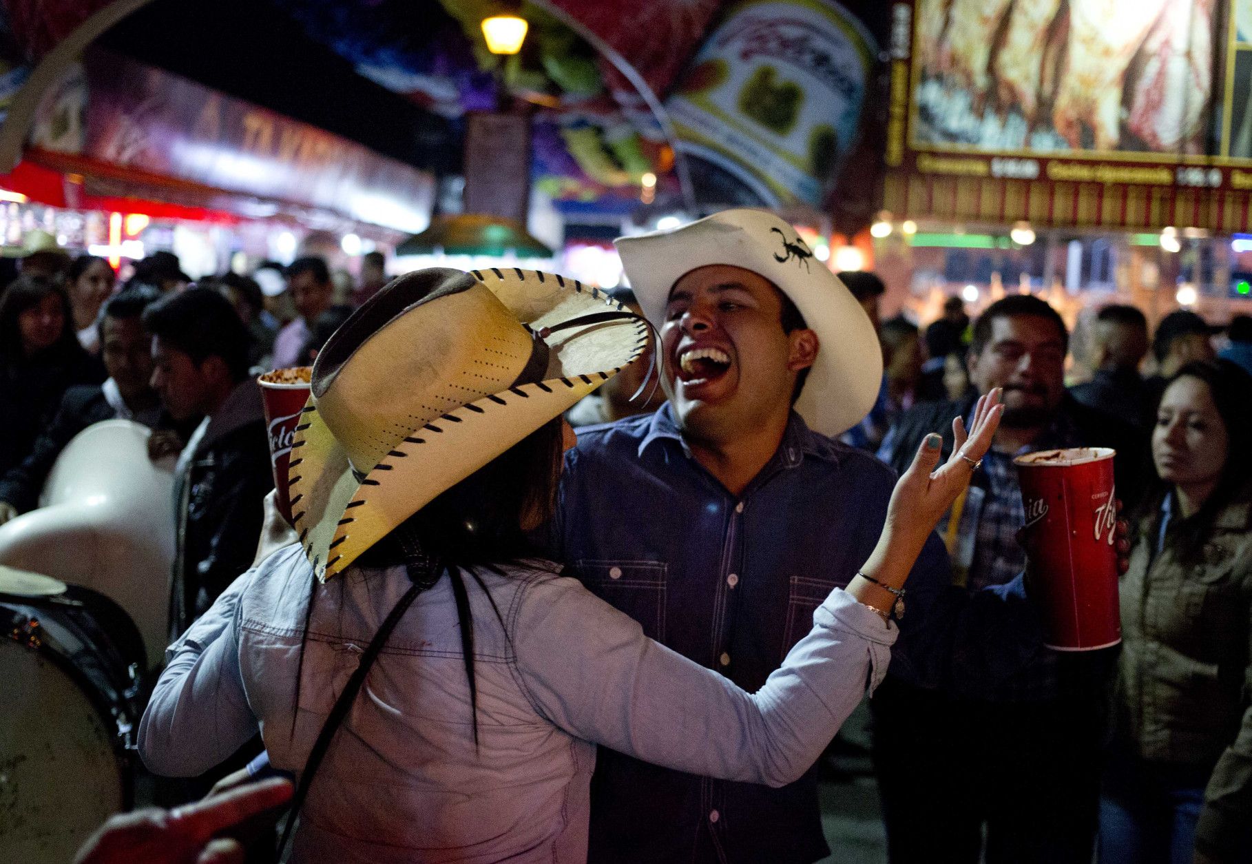 In this April 10, 2015 photo, a couple, holding michelada drinks, dances to the rhythm of a Mexican Norteño band at the Texcoco Fair on the outskirts of Mexico City. Sometimes the trumpets and tubas of the roving brassy groups clash with each other as the play songs for about $15 each. (AP Photo/Eduardo Verdugo)