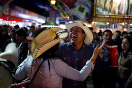 In this April 10, 2015 photo, a couple, holding michelada drinks, dances to the rhythm of a Mexican Norteño band at the Texcoco Fair on the outskirts of Mexico City. Sometimes the trumpets and tubas of the roving brassy groups clash with each other as the play songs for about $15 each. (AP Photo/Eduardo Verdugo)