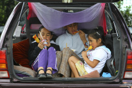 Children sit in the trunk of a car eating hotdogs in Napier, New Zealand, Sunday, Sept. 25, 2011. (AP Photo/Junji Kurokawa)