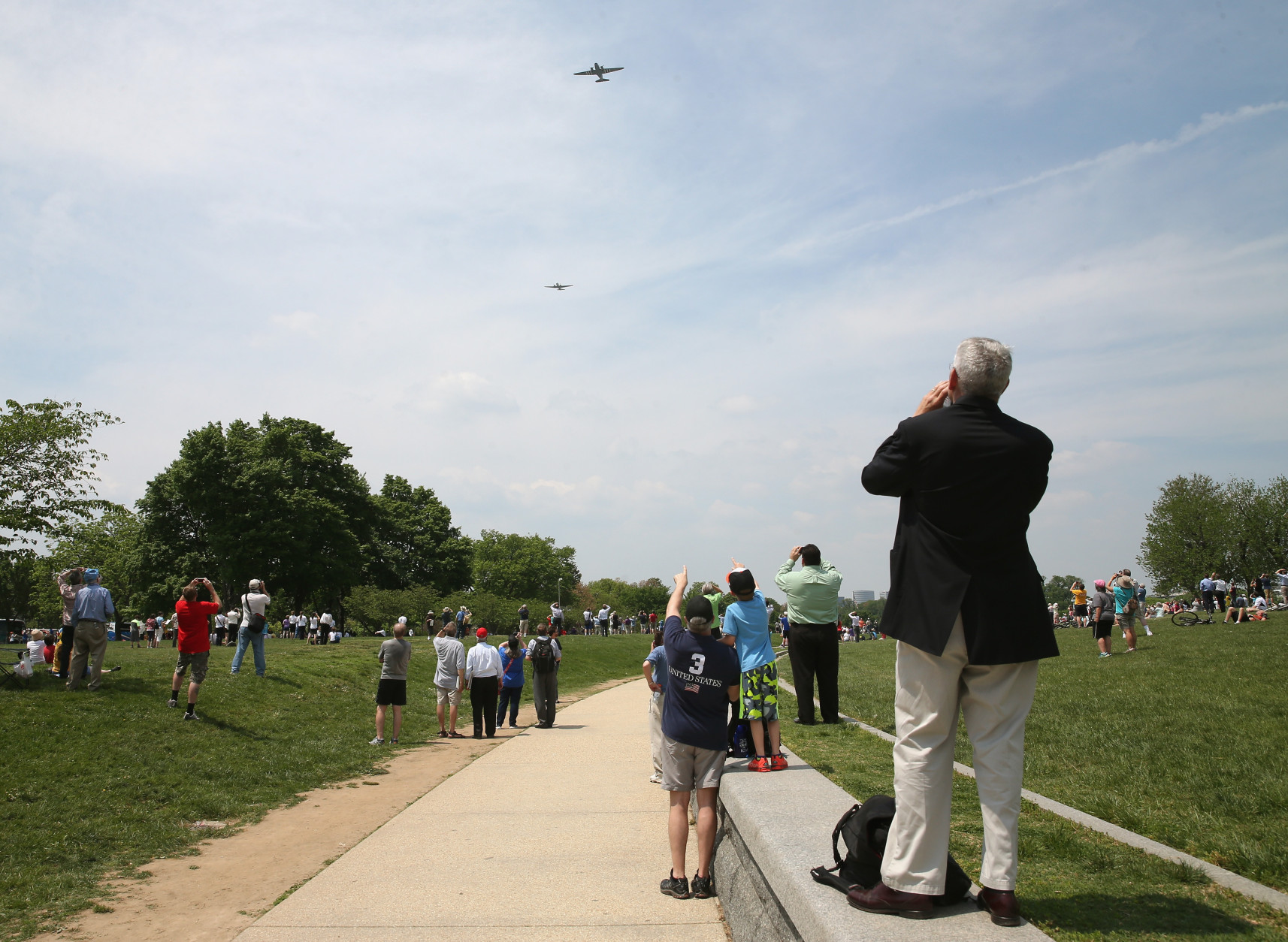 WASHINGTON, DC - MAY 08: People watch as vintage World War II war planes fly down the National Mall May 8, 2015 in Washington, DC. Fifty six vintage war planes took part in a flyover near the WWII memorial for the 70th anniversary Victory in Europe celebration. (Photo by Mark Wilson/Getty Images)
