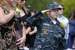 Sharon Maguire, left, of Tewksbury, Mass., holds a picture of her brother Army Spc. Fred Maguire, while standing with her nephew Sean Donahue, right, during the playing of the national anthem at the Massachusetts Military Heroes Fund flag garden on Boston Common in Boston, Thursday, May 21 2015. The fund places approximately 37,000 flags on the Common for Memorial Day to represent the Massachusetts military members who died in service from the Revolutionary War to the present. (AP Photo/Michael Dwyer)