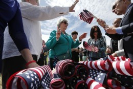 Judy Anderson, center, of North Attleborough, Mass., distributes flags to be placed in the Massachusetts Military Heroes Fund flag garden on Boston Common in Boston, Thursday, May 21 2015. The fund places approximately 37,000 flags on the Common for Memorial Day to represent the Massachusetts military members who died in service from the Revolutionary War to the present. (AP Photo/Michael Dwyer)
