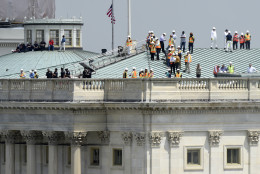 People watch vintage World War II aircraft fly over the skies of Washington, Friday, May 8, 2015, from the roof of the House of Representatives. The aircraft were flown in formations to represent the major battles of World War II. (AP Photo/Susan Walsh)