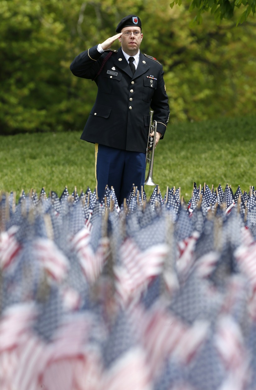 Sgt. Samuel Costa, of Somerset, Mass., salutes after playing taps at the Massachusetts Military Heroes Fund flag garden on Boston Common in Boston, ahead of Memorial Day, Thursday, May 21 2015. Each of the approximately 37,000 flags represents a Massachusetts military member who died in service from the Revolutionary War to the present. (AP Photo/Michael Dwyer)