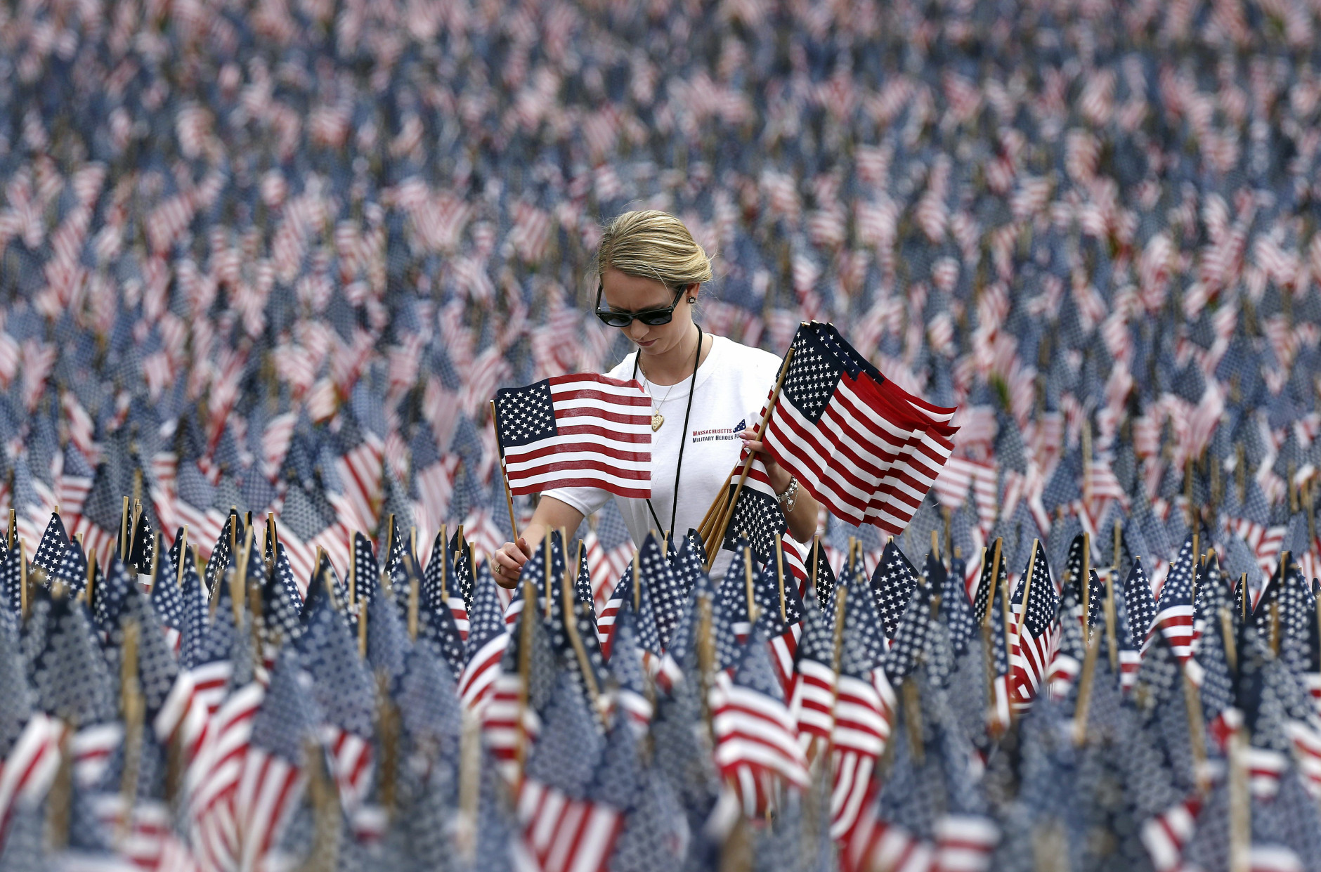 Shannon Day, of Boston, a volunteer with Massachusetts Military Heroes Fund, replaces damaged flags in the fund's flag garden on Boston Common in Boston, ahead of Memorial Day, Thursday, May 21 2015. Each of the approximately 37,000 flags represents a Massachusetts military member who died in service from the Revolutionary War to the present. (AP Photo/Michael Dwyer)