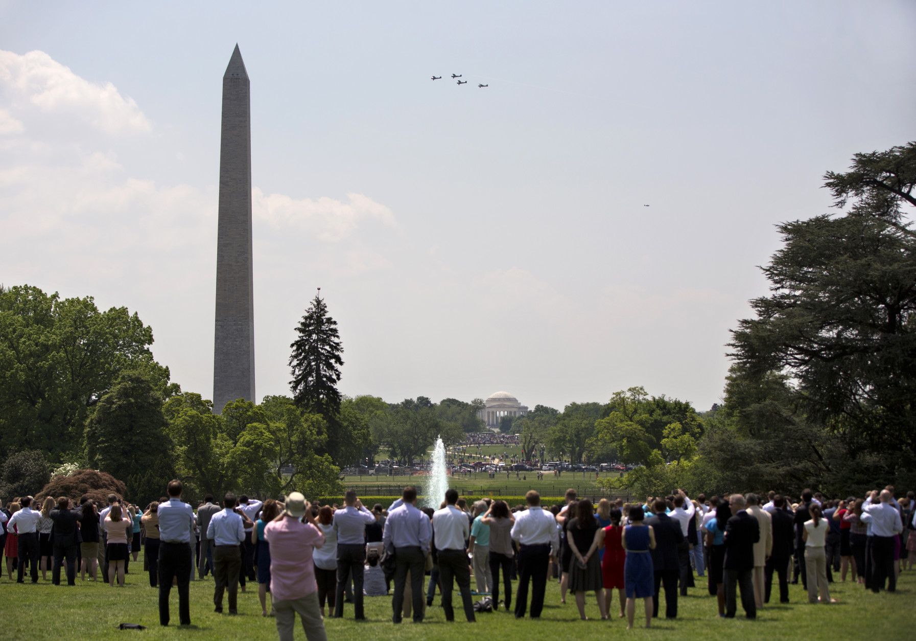 People gather on the South Lawn of the White House in Washington, Friday, May 8, 2015, to watch Vintage military aircraft from World War II fly over the Thomas Jefferson Memorial and the Washington Monument to mark the 70th anniversary of Victory in Europe Day. (AP Photo/Carolyn Kaster)