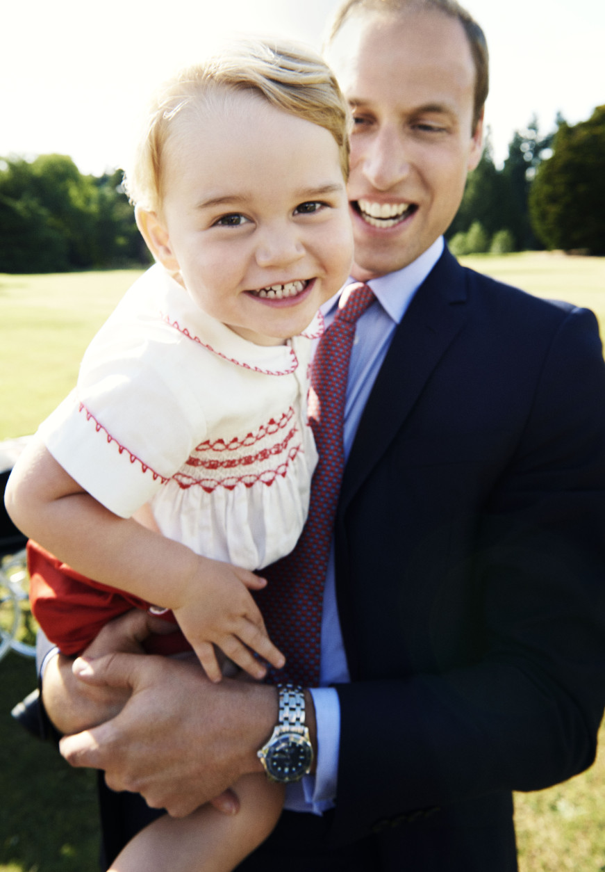 In this handout image released by Kensington Palace on Tuesday July 21, 2015, Britain's Prince William holds his son Prince George following the christening of Princess Charlotte, in the grounds of Sandringham House, England, Sunday, July 5, 2015. The photo has been released in time for Prince George's second birthday on Wednesday, July 23, 2015. (Mario Testino/Art Partner/Kensington Palace via AP)   MANDATORY CREDIT EDITORIAL USE ONLY NO NO SALES NO COMMERCIAL USE ONE TIME USE ONLY