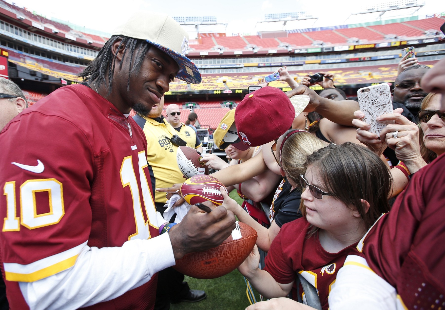 Washington Redskins quarterback Robert Griffin III, left, signs an autograph for a fan during an NFL football draft day fan fest Saturday, May 2, 2015, in Landover, Md. (AP Photo/Alex Brandon)
