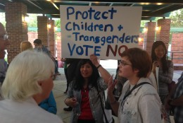 Before Thursday night's meeting, people held signs outside and discussed the issue.  (WTOP/Michelle Basch)