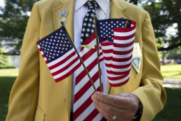 Navy veteran William Englert passes out U.S. flags to the crowd attending Memorial Day ceremonies at Arlington National Cemetery in Arlington, Va., Monday May 25, 2015.  (AP Photo/Jacquelyn Martin)