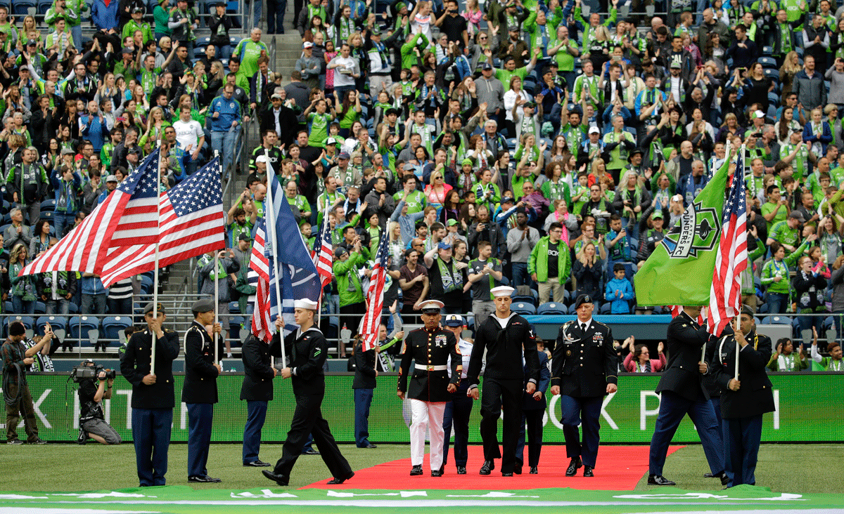 Military service members walk onto the pitch during a ceremony to honor members of the military during Memorial Day weekend before an MLS soccer match between the Seattle Sounders and Sporting Kansas City, Saturday, May 23, 2015, in Seattle. (AP Photo/Ted S. Warren)