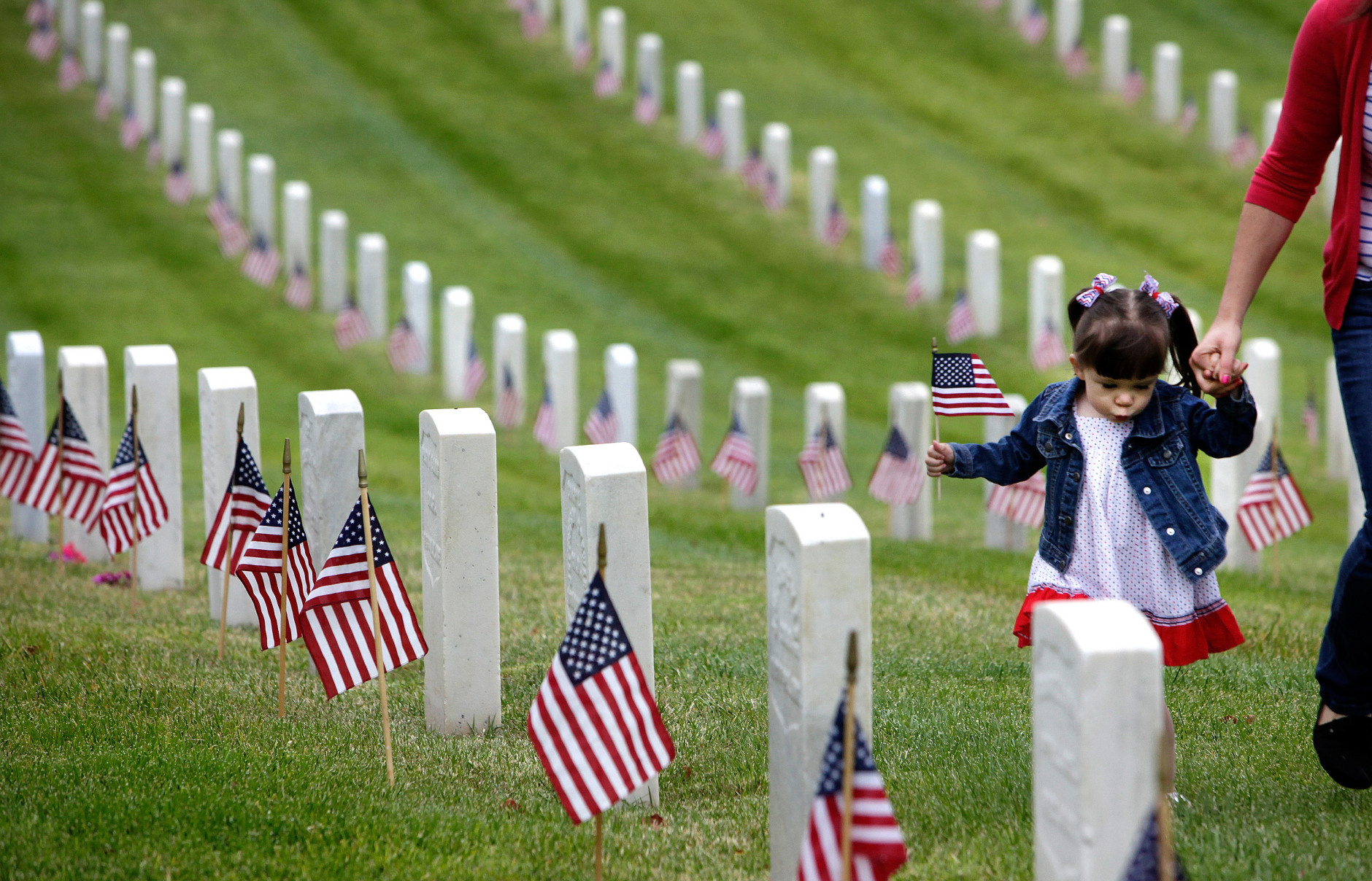 Madelyn Andrews, of Woodland Hills, Calif., walks past military graves while placing flags at headstones in remembrance of Memorial Day, Monday, May 25, 2015, at The Los Angeles National Cemetery in Los Angeles. (AP Photo/Richard Vogel)