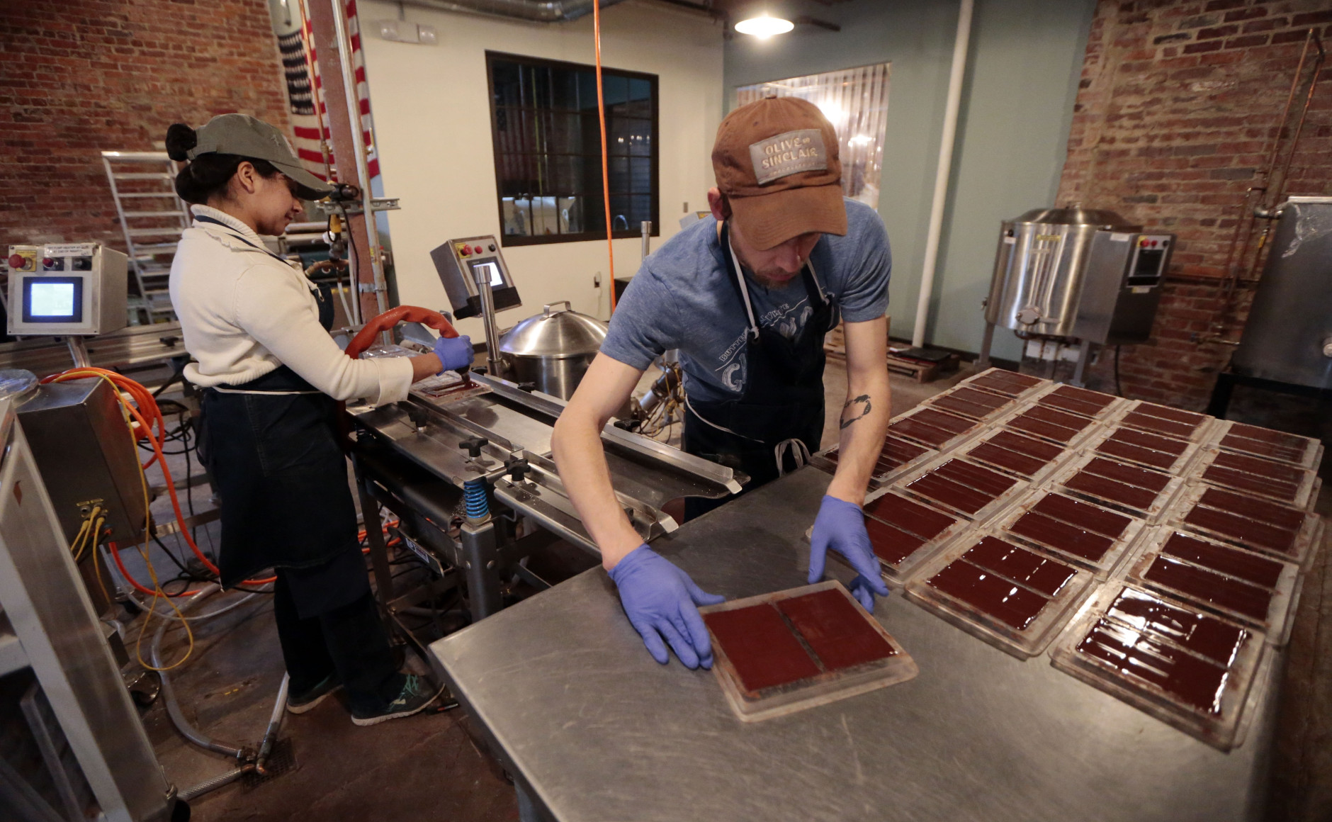 In this April 6, 2015, photo, Marta Crebilo, left, and Jason Thompson prepare chocolate molds at Olive and Sinclair Chocolate in the East Nashville area of Nashville, Tenn. The East Nashville neighborhood houses an eclectic collection of restaurants, bars, coffee shops, bakeries and stores, mixed into a residential area of 1950s and 1960s homes. (AP Photo/Mark Humphrey)