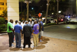 Worshippers gather to pray in a hotel parking lot across the street from the scene of a shooting Wednesday, June 17, 2015, in Charleston, S.C. (AP Photo/David Goldman)