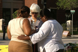  In this image taken from video on Thursday, June 18, 2015, Tarsha Moseley, left, Martha Watson, and Toby Smith pray at a makeshift memorial near Emanuel AME Church in Charleston, S.C. A white man opened fire during a prayer meeting inside the historic black church Wednesday night, killing several people. The shooter remained at large Thursday morning. (AP Photo/Alex Sanz)