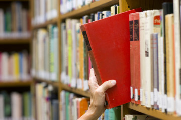 Hand pulling book off a shelf