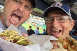 Tom Lohr, left, and his dad enjoy a Cuban at PNC Park in Pittsburgh. The all-beef frank comes with a German pretzel bun and is topped with diced ham, house-smoked pork, mustard and pickles. Lohr ranks the Cuban a 26 for a great specialty dog at a good price. (Courtesy Tom Lohr, The Hot Dog Explorer)
