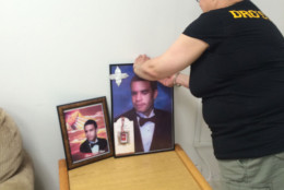 Shirley Bell of Laurel places framed pics of her slain son Brian Moses.  (WTOP/Dick Uliano)