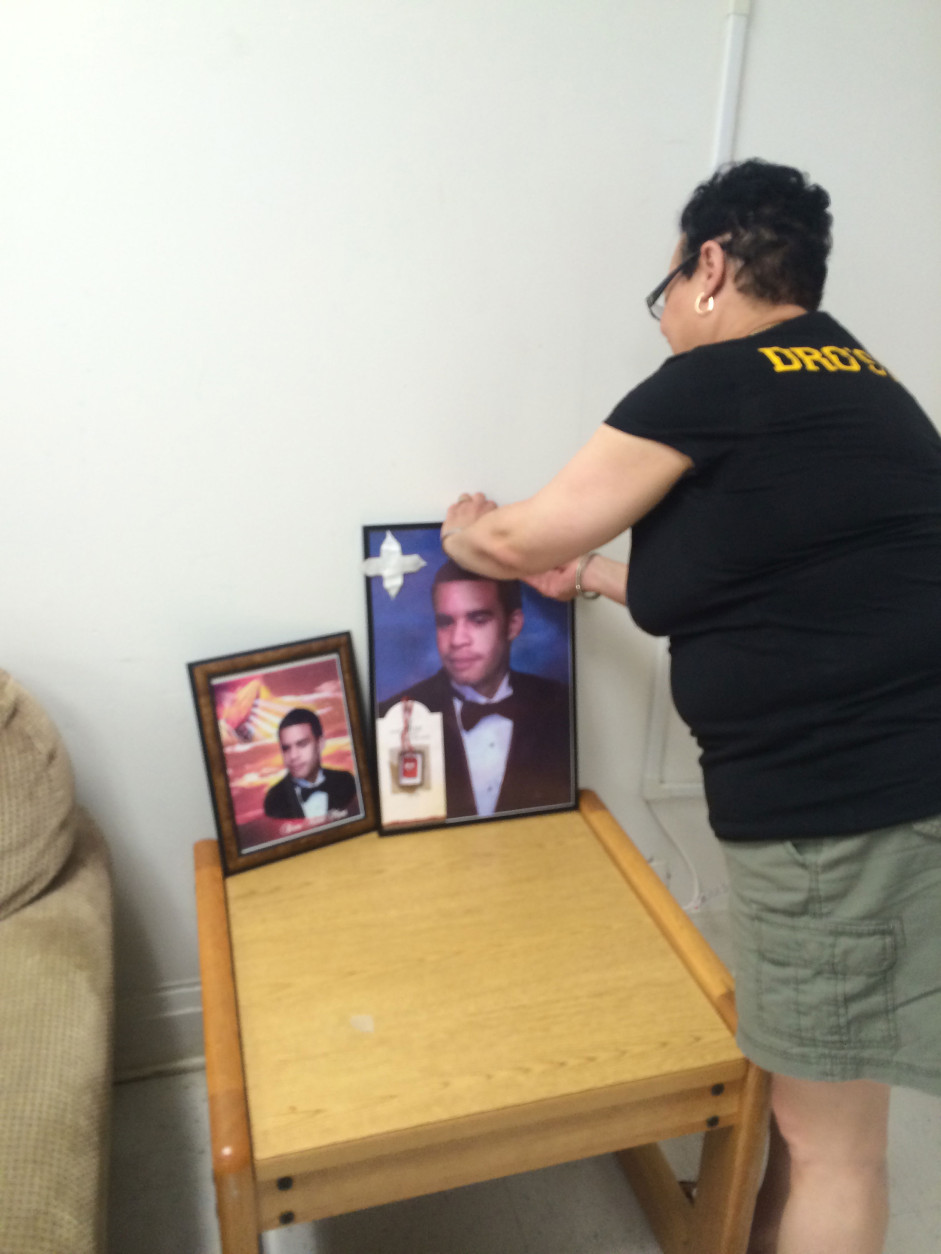 Shirley Bell of Laurel places framed pics of her slain son Brian Moses.  (WTOP/Dick Uliano)