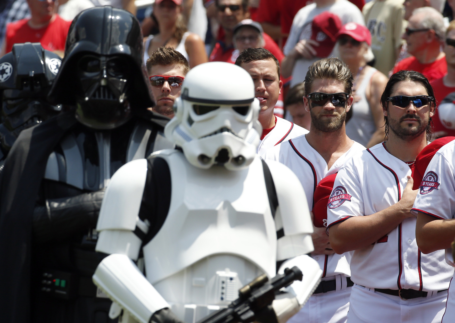 Washington Nationals' Bryce Harper, second from right, and Tanner Roark, right, stand with Darth Vader, left, and a Stormtrooper in costume during the national anthem on Star Wars Day before a baseball game against the Los Angeles Dodgers at Nationals Park, Sunday, July 19, 2015, in Washington. (AP Photo/Alex Brandon)