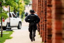 A police officer runs down M St. in Southeast Washington, Thursday, July 2, 2015, along the perimeter wall of the Washington Navy Yard. A lockdown was underway Thursday morning across the Washington Navy Yard campus after reports of shots fired, but a senior law enforcement official said those reports had not been confirmed.   (AP Photo/Andrew Harnik)
