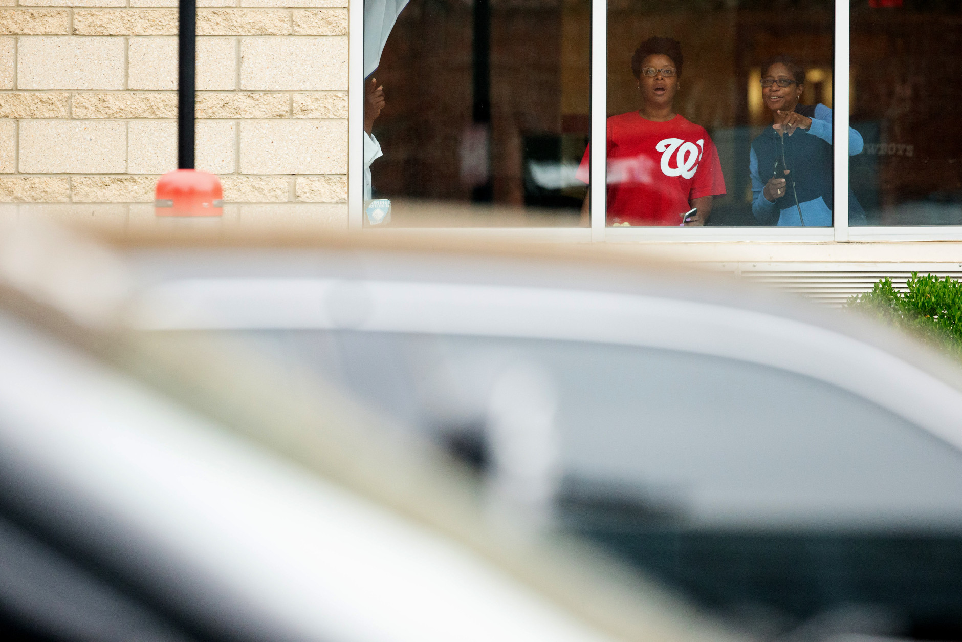 People watch out of a window at a large police presence along M St. in Southeast Washington, Thursday, July 2, 2015, near the Washington Navy Yard campus. The Washington Navy Yard was on lockdown Thursday morning after reports of gunshots, but a senior federal law enforcement official says there has been no confirmed report of any shooting.   (AP Photo/Andrew Harnik)