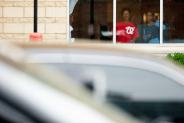 People watch out of a window at a large police presence along M St. in Southeast Washington, Thursday, July 2, 2015, near the Washington Navy Yard campus. The Washington Navy Yard was on lockdown Thursday morning after reports of gunshots, but a senior federal law enforcement official says there has been no confirmed report of any shooting.   (AP Photo/Andrew Harnik)