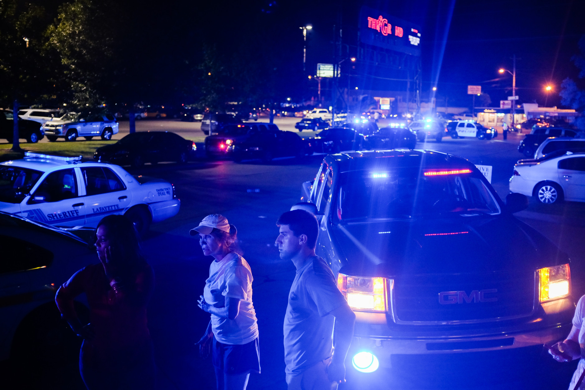 Bystanders look on as emergency personnel respond to the scene of a deadly shooting at the Grand Theatre in Lafayette, La., Thursday, July 23, 2015. (AP Photo/Denny Culbert)