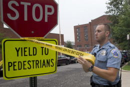 A police officer puts up police tape near the Navy Yard in Washington, Thursday, July 2, 2015. The Washington Navy Yard was on lockdown Thursday morning after reports of gunshots, but a senior federal law enforcement official says there has been no confirmed report of any shooting.  (AP Photo/Jacquelyn Martin)