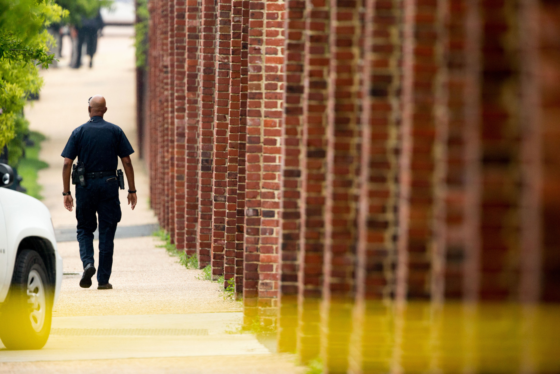 A police officer walks along the perimeter wall of the Washington Navy Yard in Washington, Thursday, July 2, 2015, after an official said shots have been reported in a building on the Washington Navy Yard campus.  (AP Photo/Andrew Harnik)