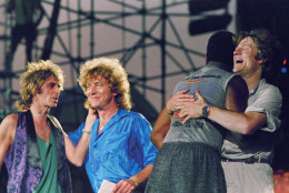Robert Plant, center, John Paul Jones, right, being hugged by Tony Thompson, back to camera, man on left is Paul Martinez during Live Aid concert on July 13, 1985. Location unknown. (AP Photo/Amy Sancetta)