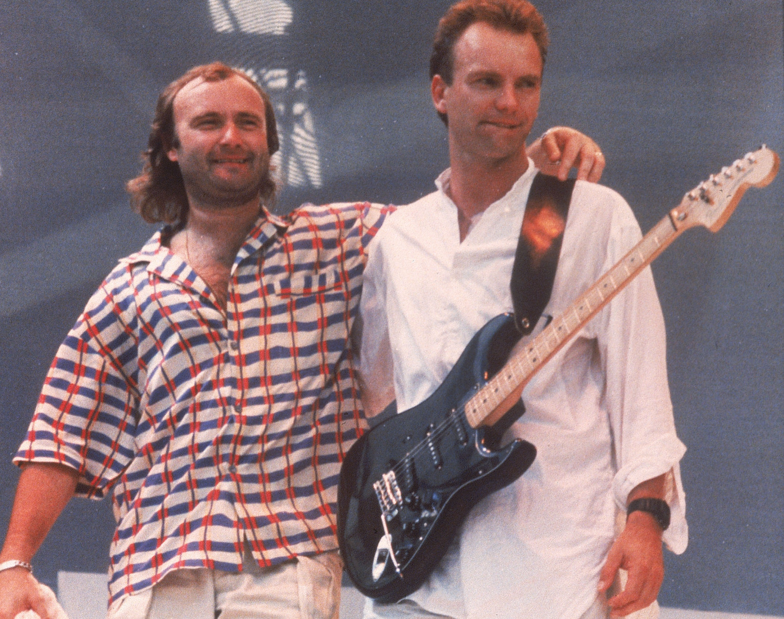 British pop singers Phil Collins, left, and Sting are shown on stage during the Live Aid concert held at London's Wembley Stadium, England, July 13, 1985.  Collins will fly on the Concorde to perform at the Live Aid concert in Philadelphia, USA.  The rock and roll telethon concert, to raise awareness for famine victims in Ethiopia, was broadcast around the world and raised $100 million dollars.  (AP Photo/Joe Schaber)