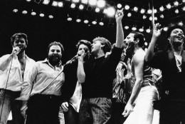 Paul McCartney,center with arm raised, joins in the finale of the London Live Aid Famine Relief Concert in London on July 13, 1985. Others, from left, are George Michael of Wham; Harvey Goldsmith, concert promoter; Bono of U2 (face obscured); McCartney; Bob Galdof, organizer; Freddie Mercury of Queen; and unidentified backing singer. (AP Photo/Joe Schaber)