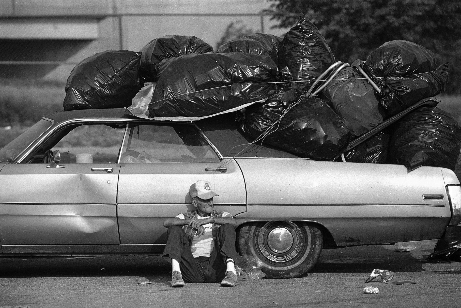 His car heeped with bags filled with aluminum cans, Charles Miller of Philadelphia takes a break from collecting the cans in the parking lots outside Philadelphia's JFK Stadium Sunday morning, July 14, 1985.  Parking lots surrounding the stadium were scattered with bottles and cans and garbage following Saturday's Live Aid concert. (AP Photo/Amy Sancetta)