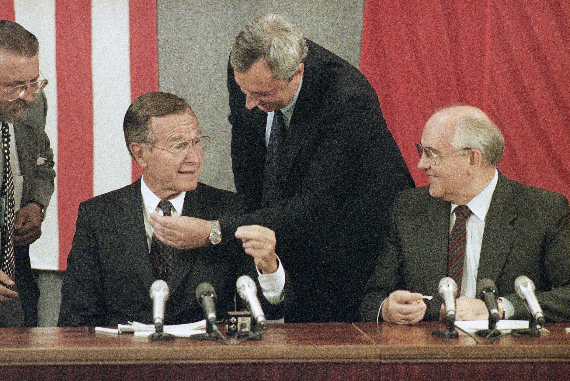 U.S. President George H. Bush and Soviet President Mikhail Gorbachev joke during their joint news conference in Moscow, Wednesday, July 31, 1991, as technician adjusts Bush's earpiece. Bush is indicating that he is listening on channel two which is used in simultaneous translation of Russian to English. (AP Photo/Marcia Nightwander)
