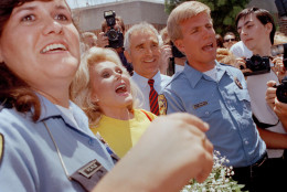 Zsa Zsa Gabor looks up at someone in the crowd as she leaves jail in El Segundo, Calif., July 30, 1990, where she spent 72 hours for slapping a Beverly Hills police officer.  At center in red necktie is her husband, Frederick von Anhalt.  (AP Photo/ Nick Ut)