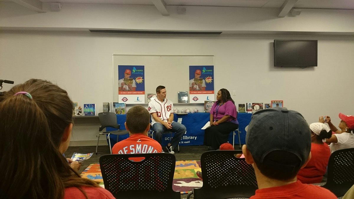 Washington Nationals starting pitcher Stephen Strasburg  chats with teacher  Joyi Better-Rice  at the Anacostia Library, where he read to young fans on Saturday,  July 18, 2015. ( Dennis J. Foley/WTOP)