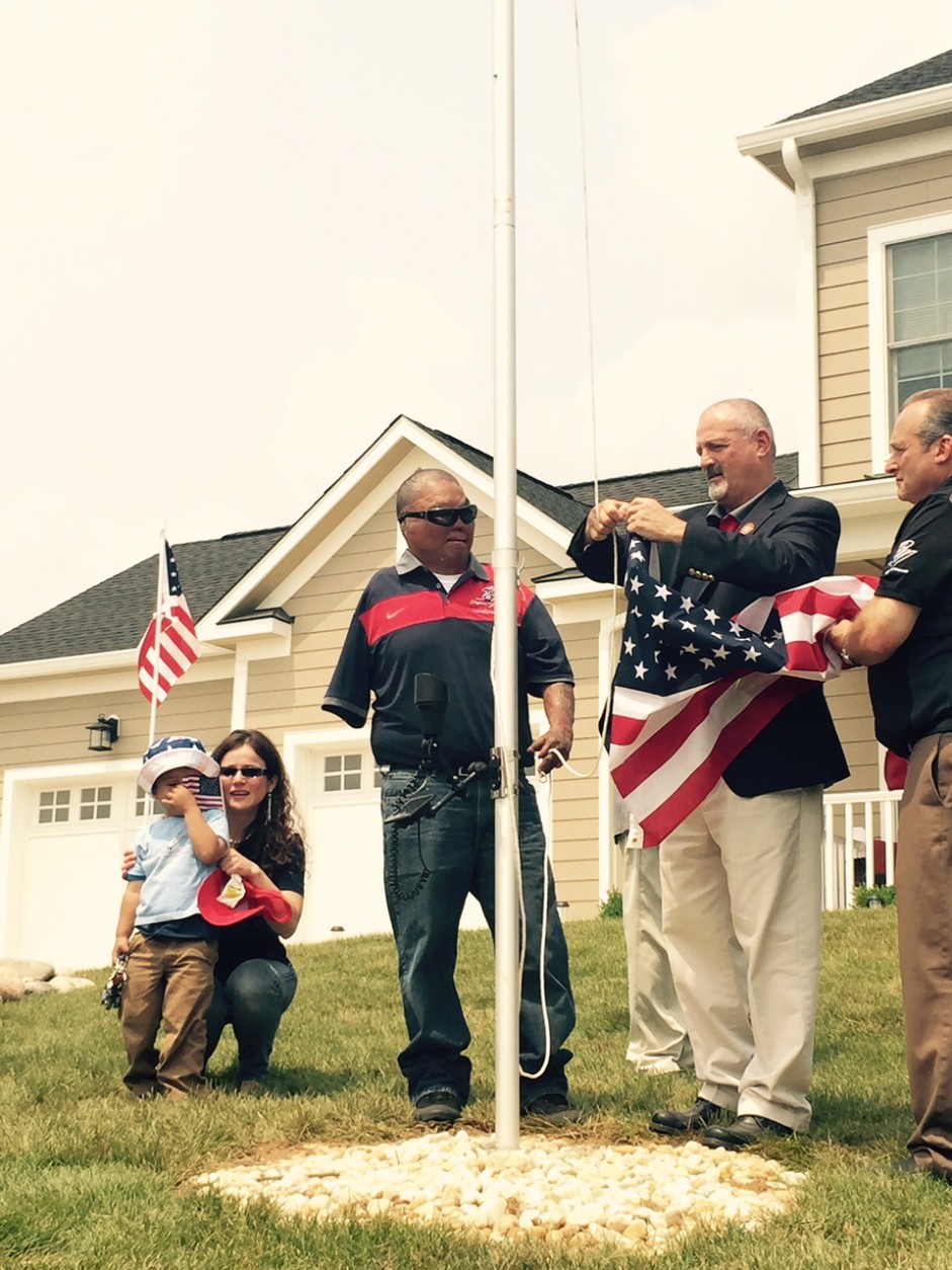 Raising the flag on the flagpole outside the house, Porta said "this is the best part." (WTOP/Max Smith)
