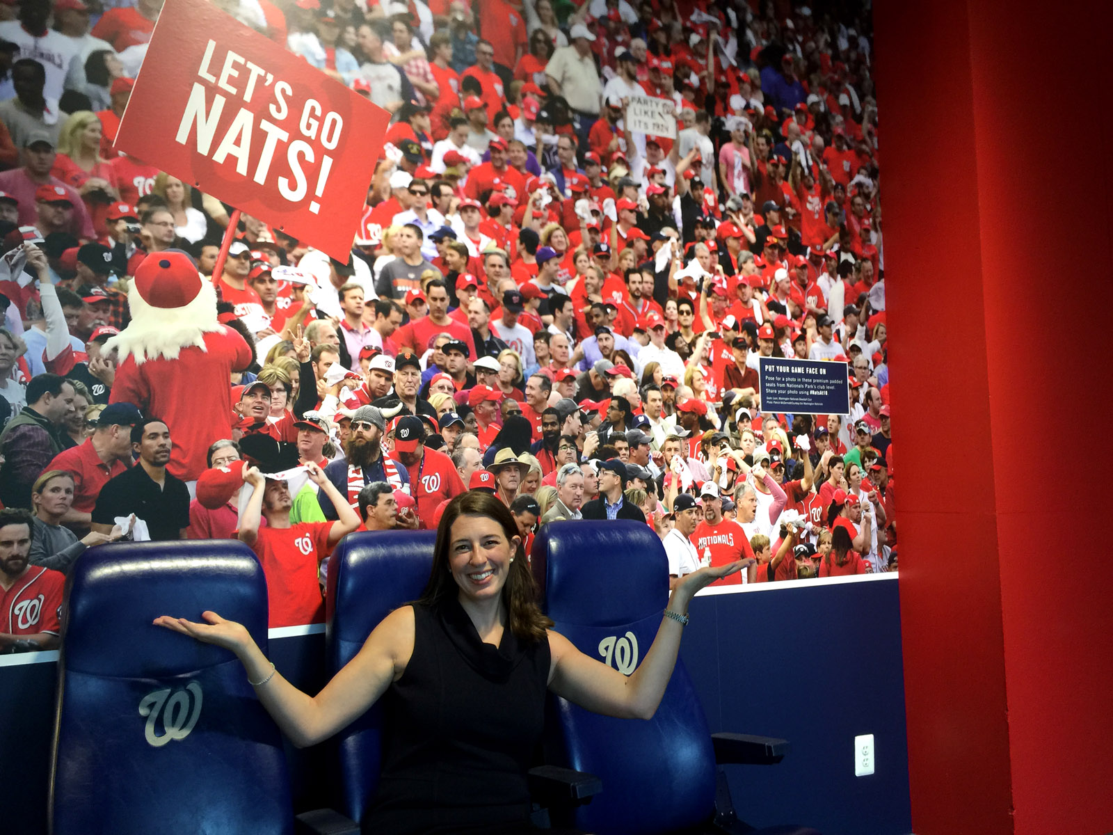 Frugal fans accustomed to the "cheap seats" can try out "premium seats" like Jennifer Giglio, Nationals vice president of communications, demonstrates at the Newseum's new exhibit featuring the first 10 years of Nationals baseball. (WTOP/Kristi King)