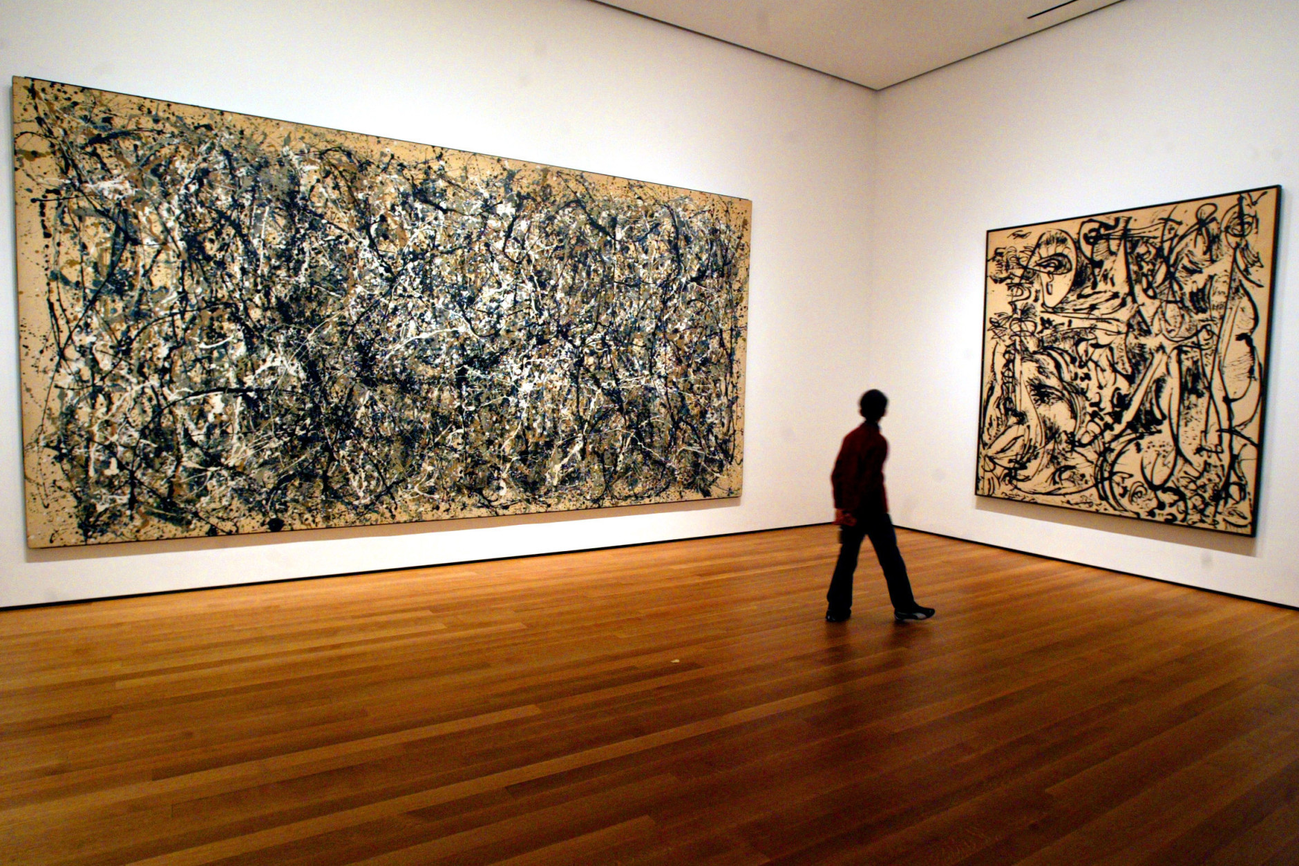 On this date in 1956, abstract painter Jackson Pollock, 44, died in an automobile accident on Long Island, New York. Here, a visitor strolls by canvasses by Abstract Expressionist Jackson Pollock at the Museum of Modern Art in New York. (AP Photo/Mary Altaffer, File)